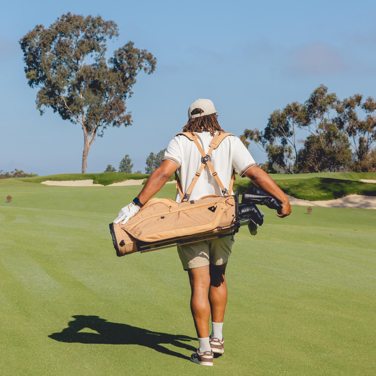 Person walking on a golf course carrying a golf bag