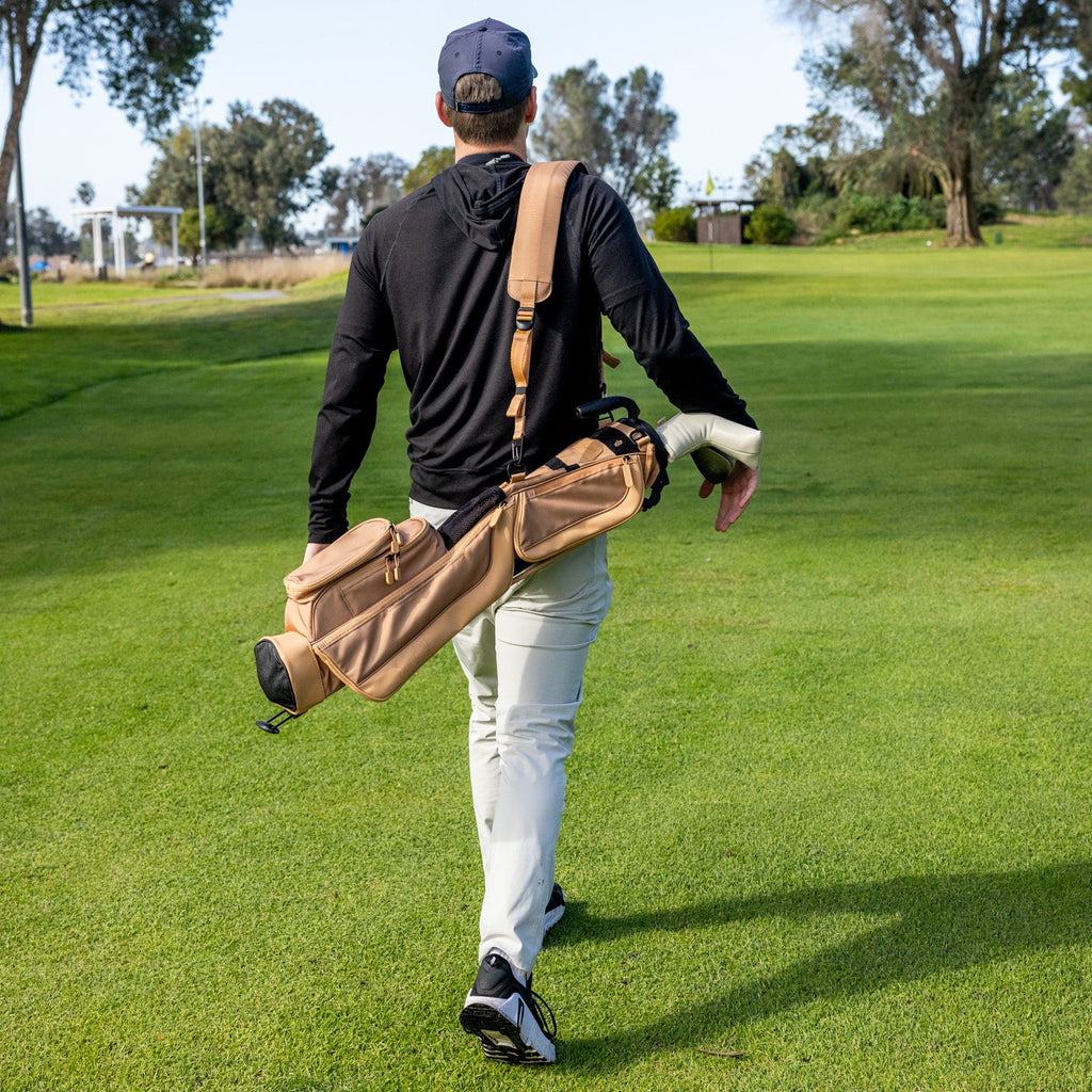 Man walking on a golf course carrying a golf bag