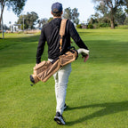 Man walking on a golf course carrying a golf bag