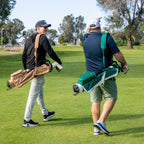 Two men walking on a golf course with golf bags.