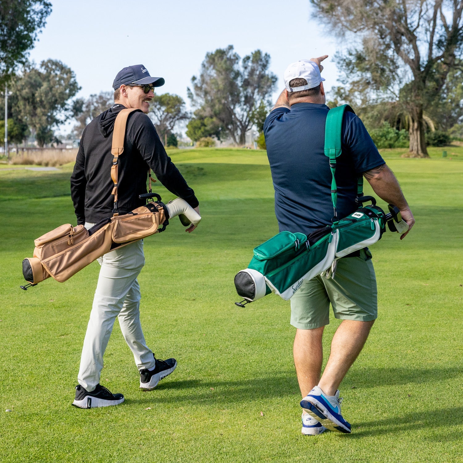 Two men walking on a golf course with golf bags.