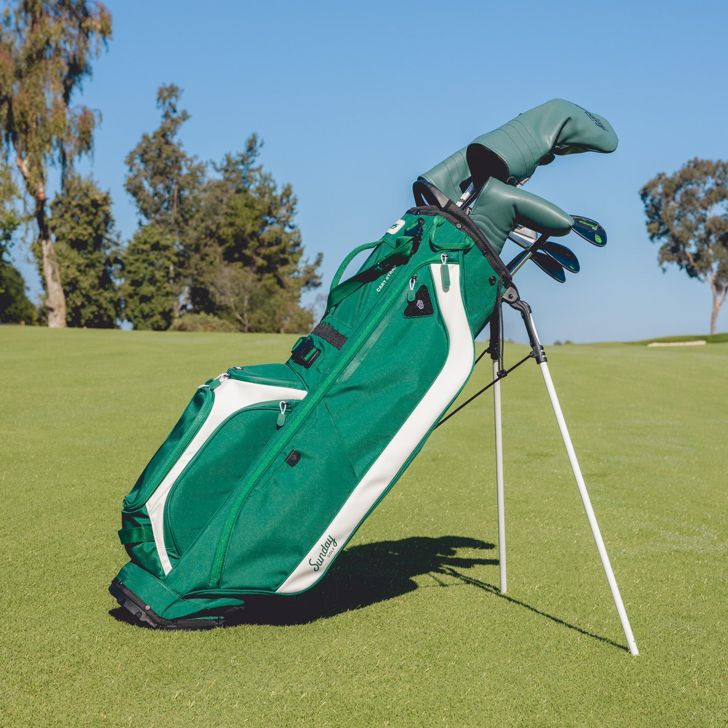 Green golf bag with clubs on a grassy field