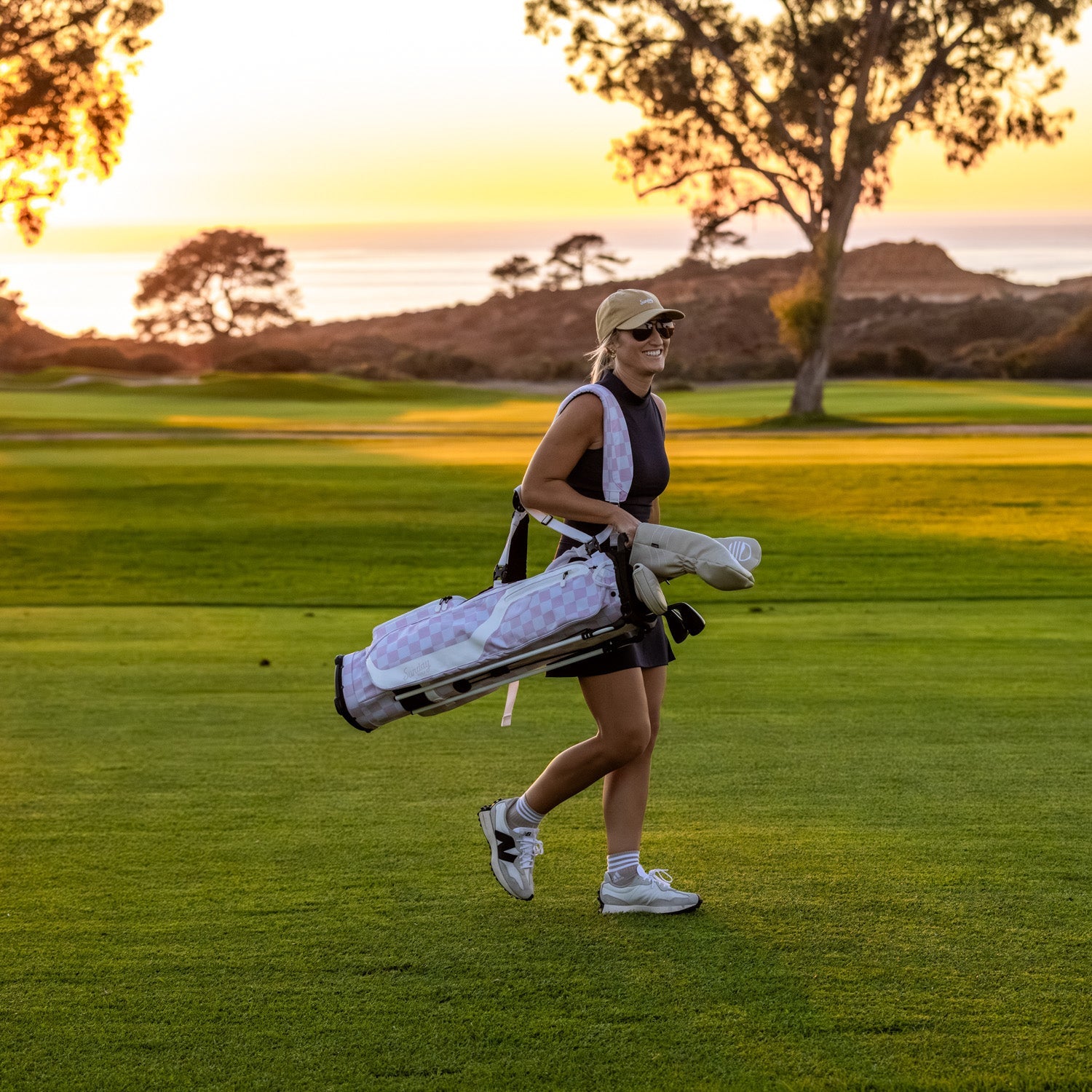 Woman walking on a golf course with a El Camino golf bag in Pink/White Checker at sunset