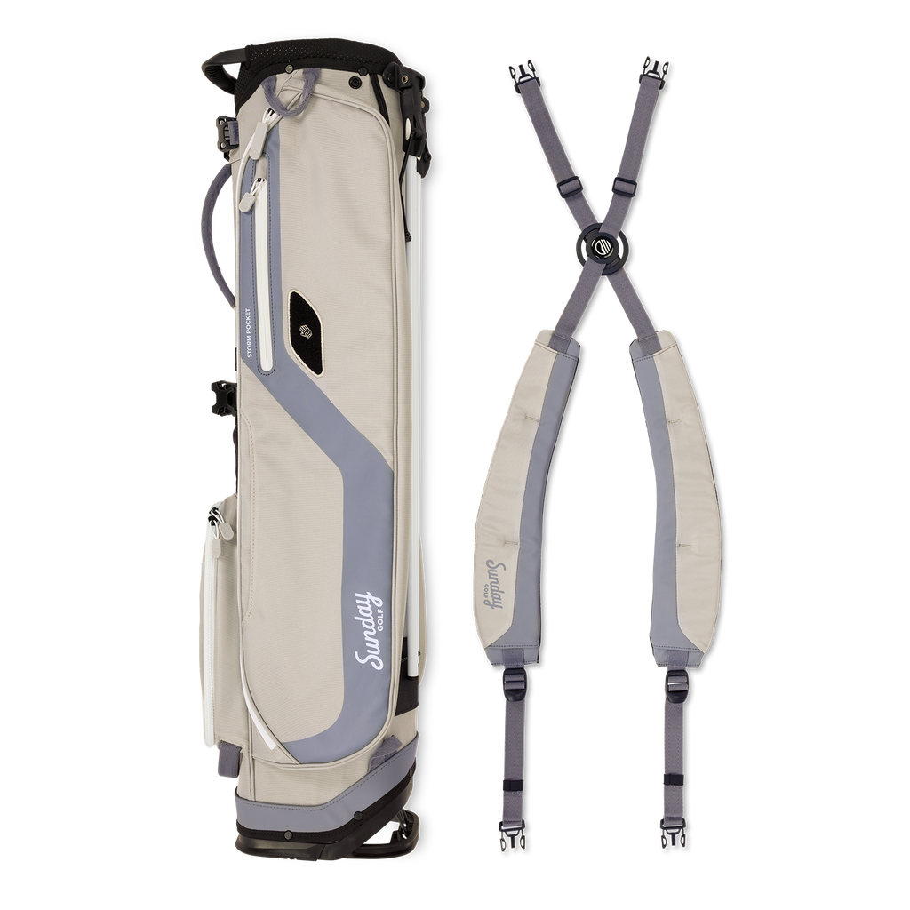 A full shot of El Camino golf bag in Cool Gray laying flat sideways beside its double strap 
